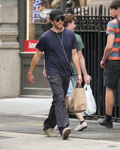 a man walking down the street with headphones in his ears, carrying a shopping bag