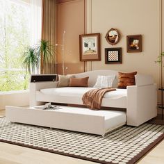 a white couch sitting on top of a rug in a living room next to a window