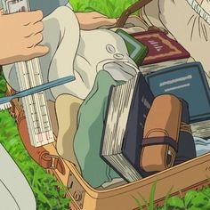 an open suitcase filled with books and other items sitting on the ground next to grass