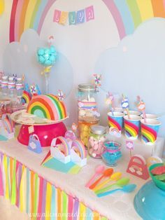 a rainbow themed birthday party with lots of food and decorations on the table, including candy