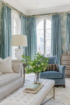 a living room filled with furniture and a large window covered in blue drapes