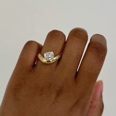 a woman's hand with a gold ring on it and a diamond in the middle