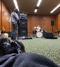 a man standing on top of a stage next to a pair of shoes and a guitar