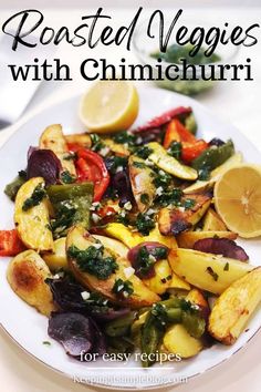 roasted veggies with cilantro and herbs on a white plate next to lemon wedges