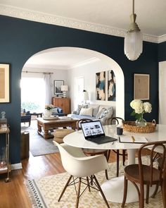 a dining room table with chairs and a laptop computer on it in front of an archway