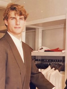 a man in a suit standing next to a closet