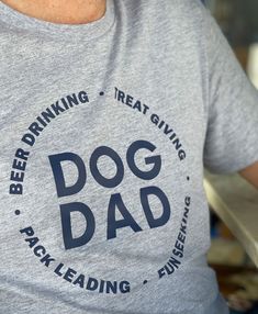 a man wearing a dog dad t - shirt while holding a hotdog in his hand