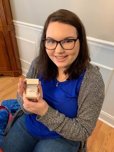 a woman sitting on the floor holding an object in her hand and smiling at the camera