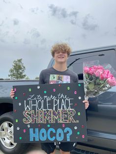 a boy holding a sign that says who's the whole place summer hoco?