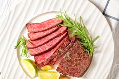 a plate with steak, lemon wedges and rosemary garnish on the side