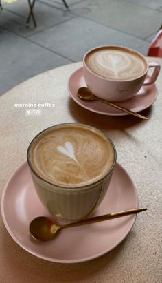 two cups of coffee sitting on top of pink saucers