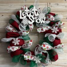 a christmas wreath with the words let it snow written on it and red, white and green mesh