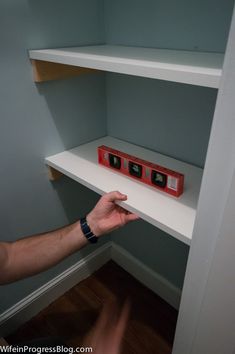 a man is reaching for an item on top of a shelf