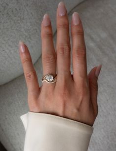 a woman's hand with a diamond ring on top of her left hand, wearing a white coat