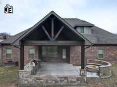 a brick house with a covered patio and fire pit in the front yard, on a cloudy day