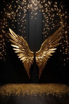 golden angel wings against a black background with gold sparkles in the foreground and on the floor