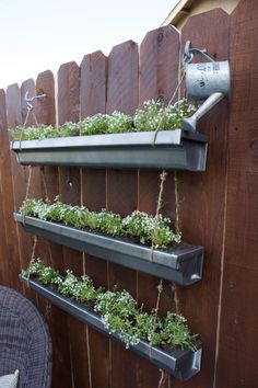 an outdoor herb garden is hanging on the side of a wooden fence with metal brackets