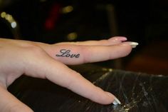 a person's hand with a small tattoo that says love on the middle finger