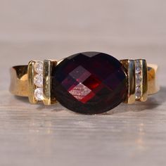 The Lawley: Checkerboard Cut Natural Garnet And Diamond Ring In Yellow Gold. This Captivating Ring Features A Central Oval Checkerboard Cut Natural Deep Orangish-Red Garnet, Elegantly Bar-Set In An East To West Orientation, Drawing Attention With Its Rich And Vibrant Hue. Surrounding The Center Are Three Round Brilliant Cut Natural Diamonds, Channel-Set To Enhance The Overall Allure Of The Piece. Crafted With Precision In 14 Karat Yellow Gold, This Ring Exudes Warmth And Sophistication. Currently Sized At 7.25, It Can Be Adjusted To Fit Any Finger Size Upon Request For An Additional Charge, Ensuring A Perfect And Comfortable Fit For The Wearer. Garnet And Diamond Ring, Onyx Engagement Ring, Channel Set, Bar Set, Red Garnet, Womens Jewelry Rings, Round Brilliant, Diamond Rings, Natural Diamonds