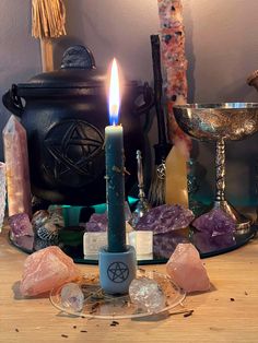 a lit candle sitting on top of a table surrounded by crystals and other things around it