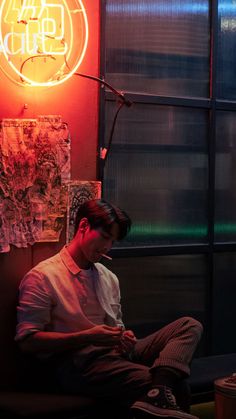 a man sitting in front of a neon sign