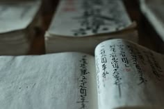 an open book sitting on top of a wooden table next to other books with writing on them