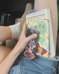 a person sitting in the back seat of a car holding a book and cell phone