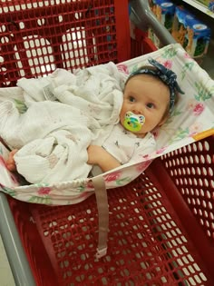 a baby in a shopping cart wearing a pacifier