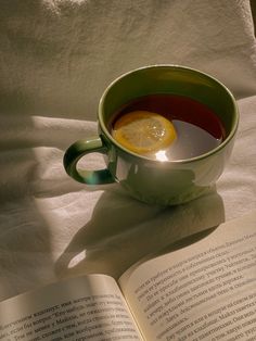 an open book with a cup of tea and lemon on it