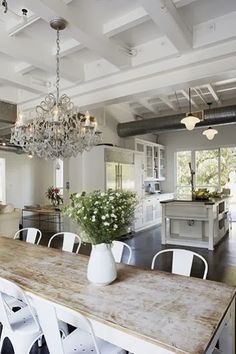 a dining room table with white chairs and a chandelier hanging from the ceiling