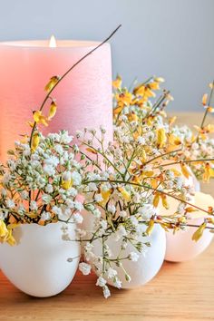 two eggs with flowers in them next to a candle