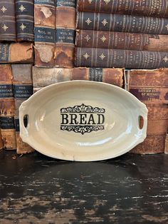 a white bread dish sitting on top of a table next to stacks of old books