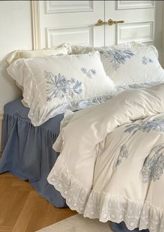 a bed with white and blue comforters on top of it in front of a door