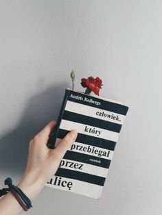 a person is holding a book with flowers on it and the cover has black stripes