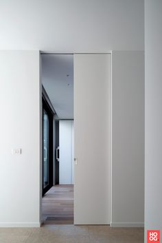 an empty room with white walls and wood flooring is seen through the open door