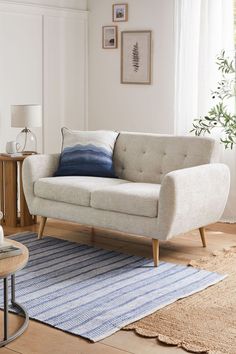 a living room scene with focus on the couch and rug in front of the window