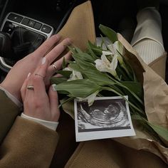 the woman is holding flowers in her hand while she sits in the driver's seat