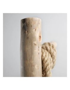 a rope wrapped around a wooden post on top of a white wall with a gray background