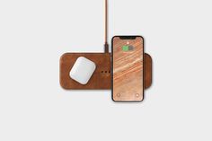 an iphone with a wireless mouse next to it on top of a wooden board and leather case