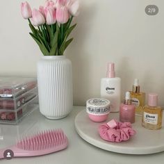 a white vase filled with pink flowers next to other beauty products