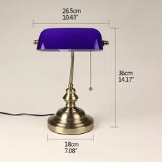 a blue lamp sitting on top of a table next to a white wall with measurements