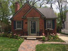 a small brick house with flowers in the front yard