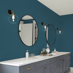 a bathroom with blue walls and two mirrors on the wall next to it is a double sink