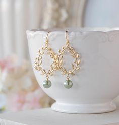 "Gorgeous gold plated laurel wreath and sage green pearl earrings. Tarnish resistant gold plated laurel wreath pendants have beautiful details on both front and back, with beautiful sage green glass pearls dangling below, hang from tarnish resistant gold plated over brass French hook ear wires. Total length: approx. 2.2\" (58mm) Laurel wreath: 25mm x 30mm Sage green pearl: 8mm More sage green pearl earrings are available here: www.etsy.com/lechaim/listing/249731049 www.etsy.com/lechaim/listing/1 Sage Green Earrings, Emerald Green Wedding Theme, Gold Laurel Wreath, Green Pearl Earrings, Wedding Earrings Chandelier, Prom Outfit, Bridal Earrings Chandelier, Green Themed Wedding, Wedding Chandelier