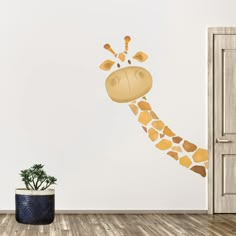 a giraffe's head is painted on the wall next to a potted plant