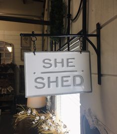 a sign that says she's shed hanging from the side of a wall next to a window