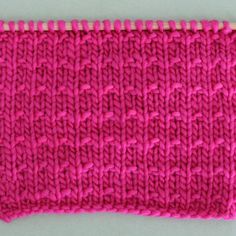 a pink knitted piece with white stitchs on it, sitting on a table