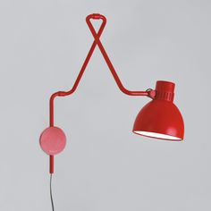 a red wall lamp with a white light on it and a pink object hanging from the side