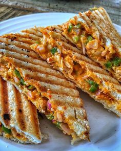 there is a sandwich cut in half on a white plate with green and yellow toppings