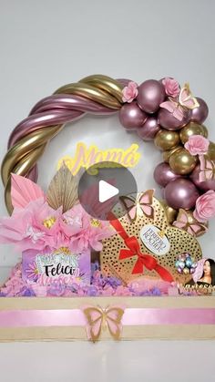 a pink and gold gift box with balloons, flowers, and other items in it